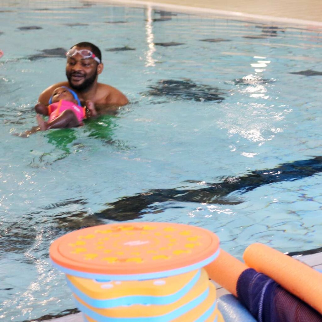 david and his daughter with a water babies mirror swimming on their back